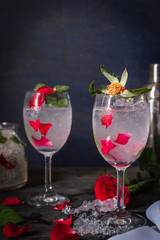 Sparkling cold water detox with rose and ice on the wood table there are rose, diferance glass, same object, cocktail shaker and ice placed around.
