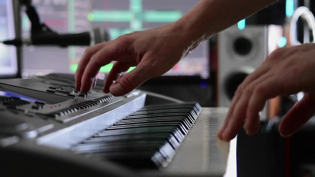 Musician's hands select sounds on a keyboard in preparation for recording in a home studio