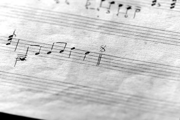 Page of an old musical notebook with hand written notes close up. Black and white