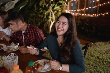 smiling asian woman enjoying their garden dinner party with friend