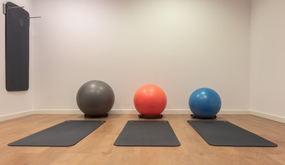 Gym for fitness exercises. Fitball and mat lie on the wooden floor. Fitness, sport, training, gym and lifestyle concept background