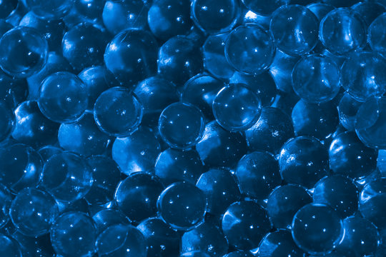 Transparent blue hydrogel balls. Blue water gel balls with bokeh. Polymer gel Silica gel. Liquid crystal ball with reflection. Blue balls texture background