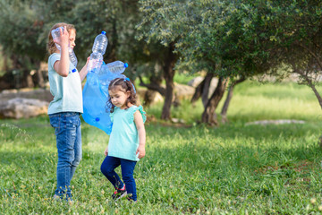 Two kids volunteer cleaning plastic pollution in summer park. Children with garbage bags cleaning up polluted environmental rubish in forest.