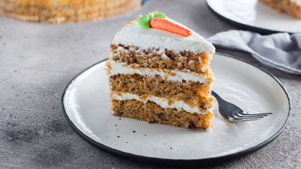 Slice of homemade carrot cake with cream cheese frosting on plate on gray stone table background - 268074987