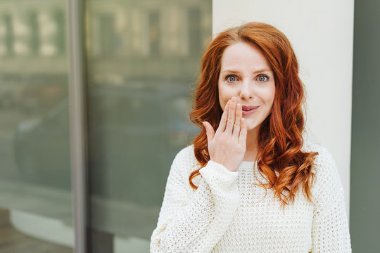 Complicit young redhead woman smiling knowingly