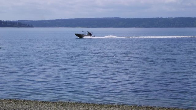 Small, nondescript fishing boat cruising past beach at Camano Island State Park, WA State. Panning. 10sec/24 fps slow motion. Version 3