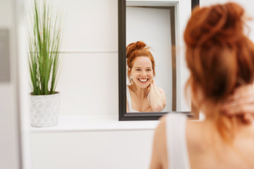 Happy young woman grinning at her reflection - obrazy, fototapety, plakaty