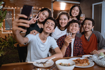 asian bestfriend group take selfie with smartphone while having garden party dinner together