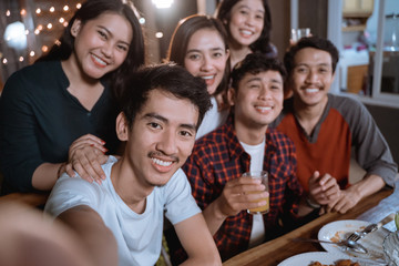 asian bestfriend group take selfie with smartphone while having garden party dinner together