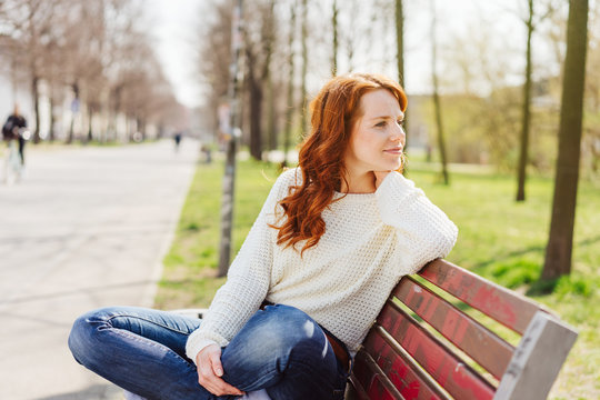 Casual relaxed young woman sitting on a park bench