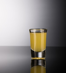 yellow alcoholic liquor in a shot glass isolated on dark background with backlight