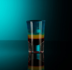 mixed alcoholic liquor in a shot glass isolated on a dark background with backlighting