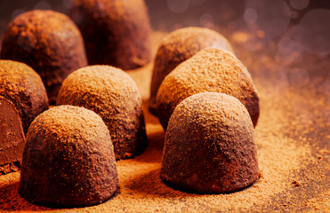 Chocolate truffles with cocoa powder on dark table, selective focus