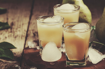Pear fresh juice with ice and fresh pear on wooden table, selective focus