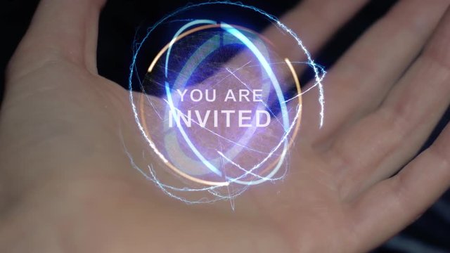 You are invited text in a round conceptual hologram on a female hand. Close-up of a hand on a black background with future holographic technology
