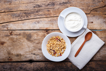 Healthy breakfast background. Muesli with yoghurt in bowl on wooden background