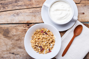 Healthy breakfast background. Muesli with yoghurt in bowl on wooden background