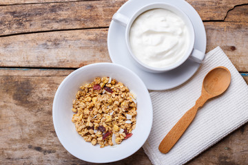 Healthy breakfast background. Muesli with yoghurt in bowl on wooden background