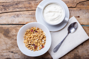 Healthy breakfast background. Muesli with yoghurt in bowl on wooden background