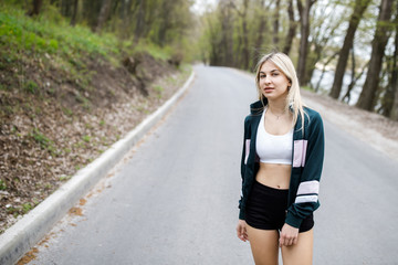 Fototapeta na wymiar A young, pretty girl blonde is training before running outdoors. Sports activity. Exercise Outdoors. Health and benefits for the body