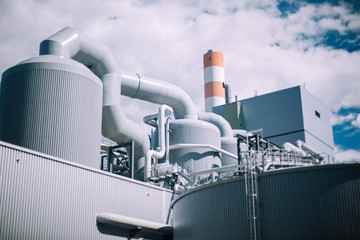 Silos and pipes stand against the cloudy blue sky at a pulp mill in Stendal, Germany
