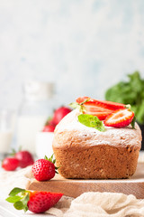 Pound or loaf cake with strawberry and mint on wooden board. Delicious summer dessert.