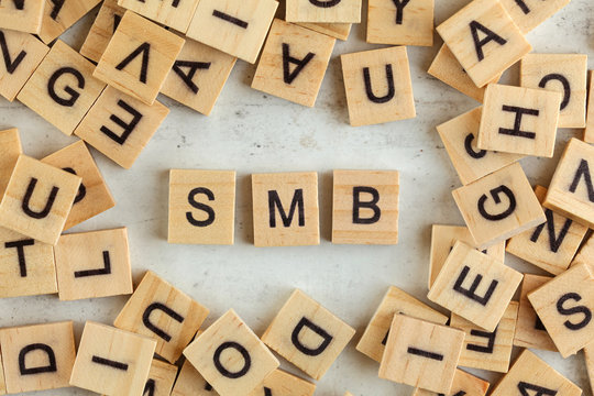 Top down view, pile of square wooden blocks with letters SMB (stands for Small to Medium Business ) on white board.