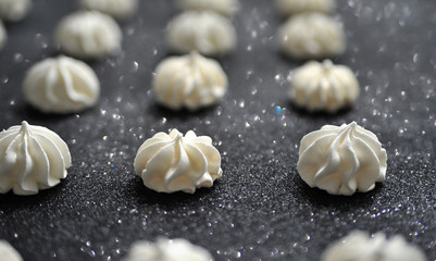 Meringues on glitter black background.