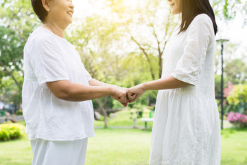 Hand of asian female elderly giving fist bump to hands young women at outdoor in garden,Happy and smiling