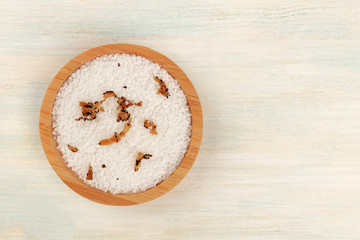 A bowl of sea salt infused with truffle shavings, shot from the top on a white wooden background with copy space