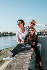 Young family sitting together on the river embankment relaxed