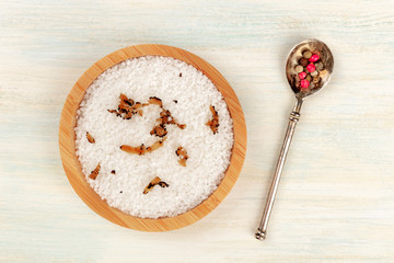 Gourmet spices. A bowl of sea salt infused with truffle shavings and a pepper mix, shot from the top on a white wooden background with copy space