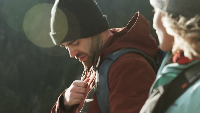 Man and woman hiking in winter, man stops to take out old compass