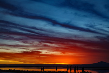 Fototapeta na wymiar Sunset in salar with orange sky and tourist silhouettes