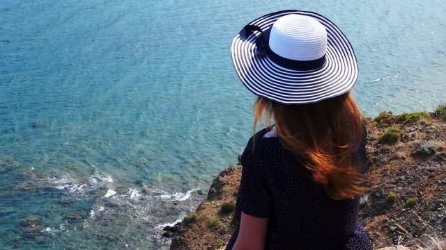 Redhead girl looks from a hill on the Mediterranean Sea in Phaselis. City of ancient Lycia. Turkey.