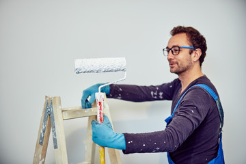 Worker painting walls inside the house - renovation fixes.