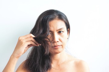Fototapeta premium Middle aged Asian woman worried about damaged hair. Healthy and beauty concept