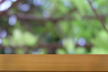 Image of wooden table in front of abstract blurred background of outdoor garden lights. can be used for display or montage your products.Mock up for display of product.