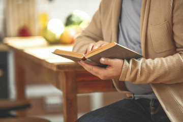 Handsome mature man reading cook book in kitchen