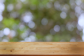 Image of wooden table in front of abstract blurred background of outdoor garden lights. can be used for display or montage your products.Mock up for display of product.