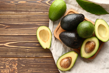 Board with fresh avocado on wooden background