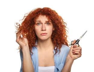 Obraz premium Beautiful woman displeased with her hair holding scissors on color background