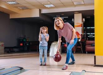 Woman and her little daughter playing bowling in club