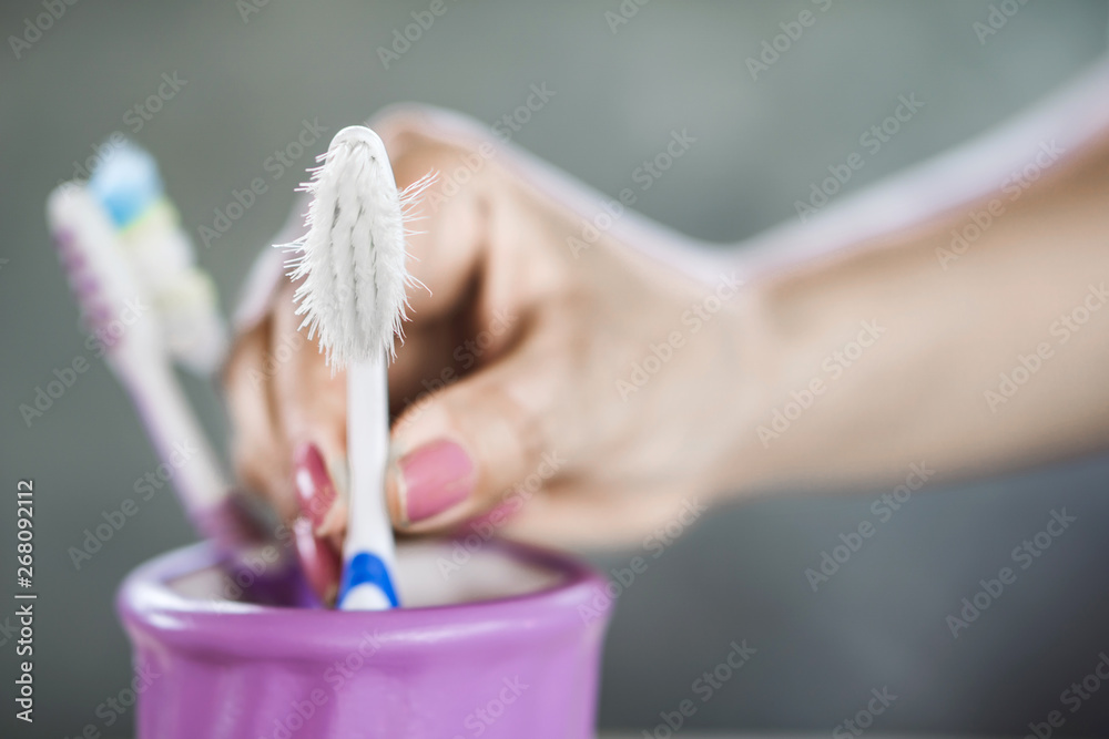 Wall mural woman hand using old and destroy toothbrush closeup