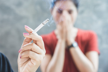 Asian woman smoking cigarette near people in family smelling pollution,passive smoking concept