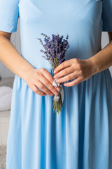 A girl in a blue dress holds a bouquet of lavender in her hands.