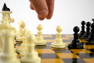 the chess player's hand moves the pawn on a board during the game of chess