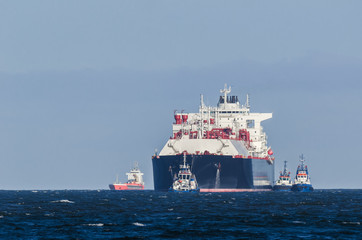 LNG TANKER - A large ship belayed by tugboats travels by water to the port © Wojciech Wrzesień