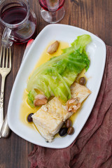 boiled cod fish with olive oil and vegetables on white plate