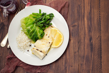 boiled cod fish with rice and vegetables on white plate